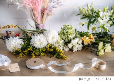 Selection of fresh florals including chrysanthemums, hydrangeas, and solidago laid out on a florists worktable. Mindful crafting, autumn floral creativity, slow floristry, nature-inspired design 131980183
