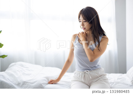 窓からの朝日を浴びながら肩をマッサージする若い女性 窓からの朝日を浴びながら肩をマッサージする若い女性 131980485