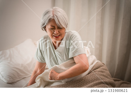 ベッドルームで寝起きに苦しい表情をするグレイヘアーのシニア女性 ベッドルームで寝起きに苦しい表情をするグレイヘアーのシニア女性 131980621