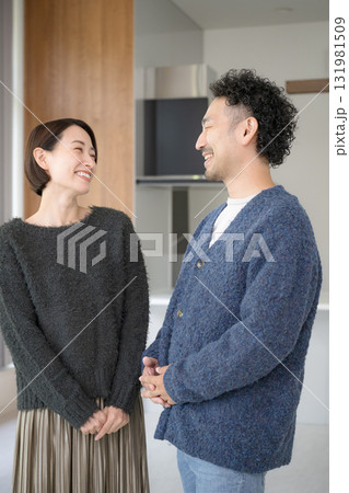 明るいリビングでリラックスする40代の夫婦で見つめ合う　自宅の新築やライフスタイルイメージの秋冬 131981509