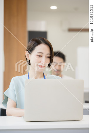 社内でデスクワークする女性　フリーアドレスのイメージ	 131981513
