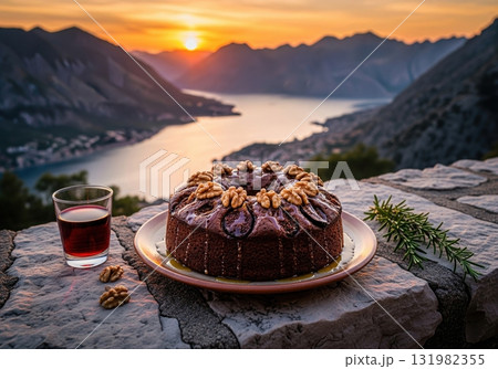 Montenegrin fig and walnut cake with red wine during a beautiful sunset over a mountain bay Montenegrin fig and walnut cake with red wine during a beautiful sunset over a mountain bay 131982355