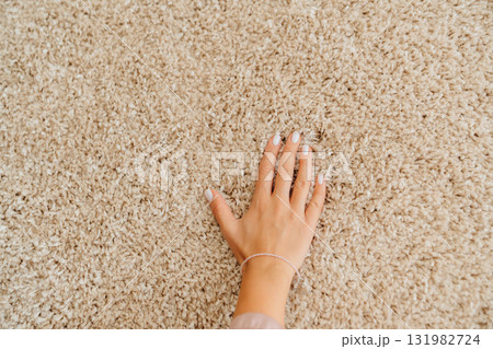 a woman's hand touching the beige Interior pile carpet made of polypropylene. a woman's hand touching the beige Interior pile carpet made of polypropylene. 131982724