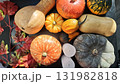 Various colorful pumpkins and gourds arranged with red autumn leaves on a dark background 131982818