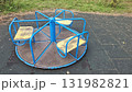 Old blue and yellow playground carousel on rubber tiles in an empty park 131982821