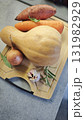 Fresh vegetables arranged on a wooden cutting board including butternut squash, sweet potato, carrot, onion, and garlic. Concept of healthy cooking ingredients and autumn seasonal food 131982929