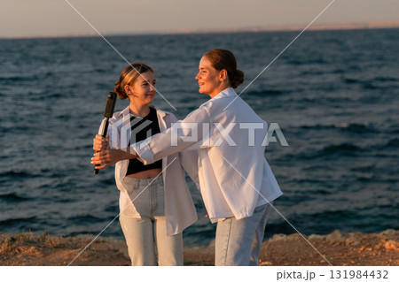 Beach, Girls, Baseball Bat - Two girls practicing with a baseball bat near the sea at sunset. 131984432