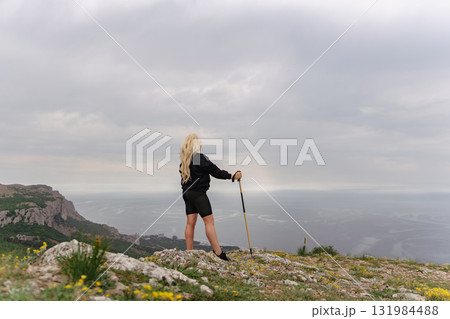 A woman stands on a rocky hill overlooking the ocean 131984488