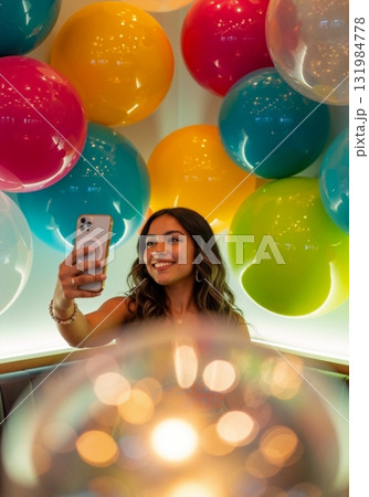 Young Hispanic woman taking a selfie with a smartphone. Smiling female in a vibrant, colorful balloon-decorated setting. Modern lifestyle and social media concept Young Hispanic woman taking a selfie with a smartphone. Smiling female in a vibrant, colorful balloon-decorated setting. Modern lifestyle and social media concept 131984778