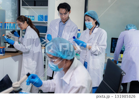 Team of biochemical research scientists working with a microscope for vaccine development 131985826