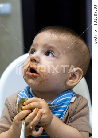 Baby with Food on Face Holding Spoon Baby with Food on Face Holding Spoon 131985993