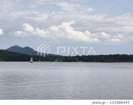 A serene lake scene with a sailboat and majestic mountains during a beautiful sunset A serene lake scene with a sailboat and majestic mountains during a beautiful sunset 131986445