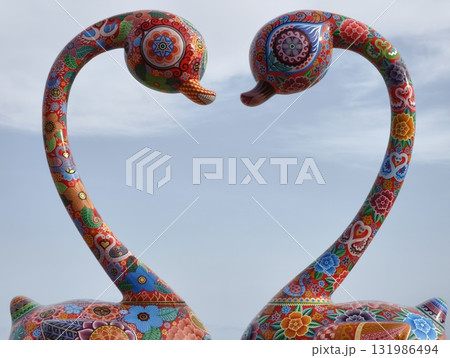 A Pair of Colorful Artistic Swans Gracefully Facing Each Other in Serene Harmony 131986494