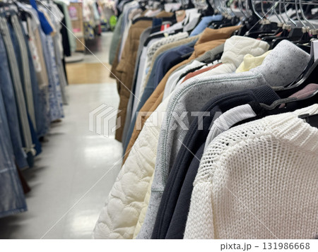 A clothing store rack filled with sweaters and jackets arranged neatly in a shopping aisle A clothing store rack filled with sweaters and jackets arranged neatly in a shopping aisle 131986668