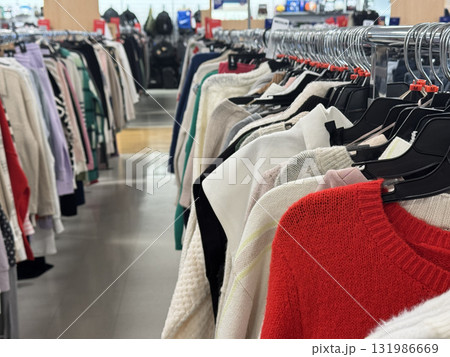 A clothing rack in a retail store displaying colorful sweaters and garments neatly arranged for shoppers 131986669
