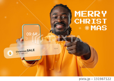 Happy man shows smartphone with special Christmas sale on an orange background Happy man shows smartphone with special Christmas sale on an orange background 131987122