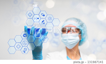 Scientist holds blue liquid in a flask while examining digital health icons Scientist holds blue liquid in a flask while examining digital health icons 131987141