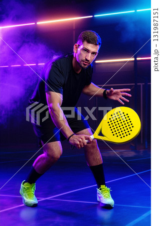 Young athlete prepares for intense paddle match in neon-lit sports facility Young athlete prepares for intense paddle match in neon-lit sports facility 131987151