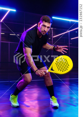 Padel player in action on a brightly lit court at night Padel player in action on a brightly lit court at night 131987152