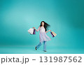 Young woman carrying shopping bags against a blue background 131987562