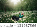 Young woman relaxing in a daisy field during golden hour 131987566