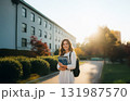 Young woman holding books on campus at sunset, happy mood 131987570