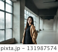 Young woman in camel coat standing in a modern building 131987574