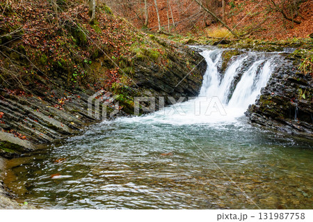 autumn scenery with waterfall. stones seen through transparent water. orange foliage on the hill. cascades of the river turychka in fall season. overcast weather. travel destination of transcarpathia autumn scenery with waterfall. stones seen through transparent water. orange foliage on the hill. cascades of the river turychka in fall season. overcast weather. travel destination of transcarpathia 131987758