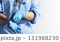 Healthcare professional putting on blue medical gloves on white background with copy space 131988230