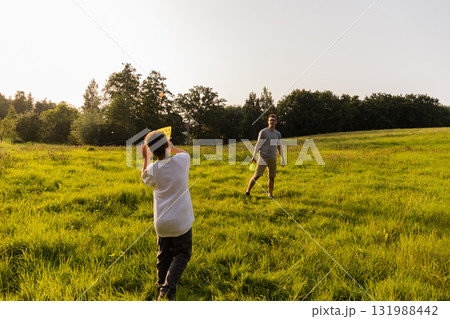 A father and son share joyful moments as they play catch in a vibrant green field. The sun shines brightly, creating a warm and enjoyable atmosphere for their outdoor adventure 131988442