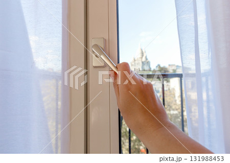 A woman's hand opens a window 131988453