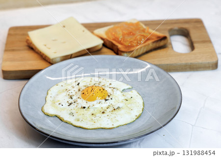 Breakfast served on the kitchen table with a fried egg on a plate and fresh bread and coffee 131988454