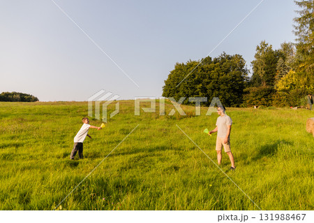 A father and son share quality time outdoors, playing catch on a sunny day. The lush green grass surrounds them as they laugh and enjoy their time in nature A father and son share quality time outdoors, playing catch on a sunny day. The lush green grass surrounds them as they laugh and enjoy their time in nature 131988467