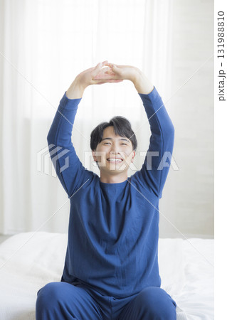 ベッドで伸びをする男性　  131988810