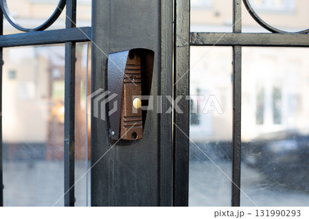 Doorbell installed on black metal gate, button clearly. Simplicity and functionality of design, perfect for topics related to home security, entrance systems and access control in residential areas 131990293