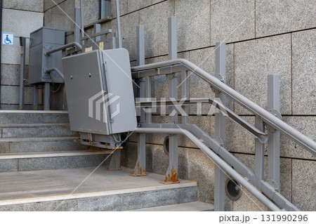 Elevator lift for people with disabilities at building stairs. Emphasizes accessibility with metallic design and functionality to ensure inclusivity in public spaces. Creating accessible environment Elevator lift for people with disabilities at building stairs. Emphasizes accessibility with metallic design and functionality to ensure inclusivity in public spaces. Creating accessible environment 131990296