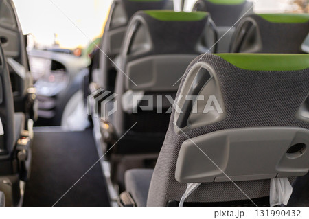 The interior of a bus shows rows of modern seats designed for comfort. Bright lighting enhances the welcoming atmosphere. Ideal for a relaxed journey through the city The interior of a bus shows rows of modern seats designed for comfort. Bright lighting enhances the welcoming atmosphere. Ideal for a relaxed journey through the city 131990432