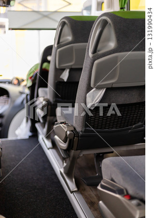 Inside a bus, the image shows a row of empty seats with a view towards the front. The bus is clean, providing a calm atmosphere for travelers during the day Inside a bus, the image shows a row of empty seats with a view towards the front. The bus is clean, providing a calm atmosphere for travelers during the day 131990434