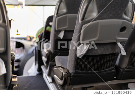 Inside a city bus during the daytime, the scene shows empty seats arranged neatly. The atmosphere is calm with sunlight filtering through the windows, highlighting the interior details 131990439
