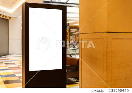 A digital display stand is positioned in a modern lobby area. The sleek design features a blank screen, offering space for advertisements 131990440