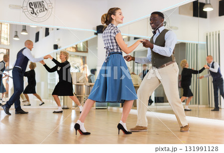 Woman with african man practising charleston dancing 131991128