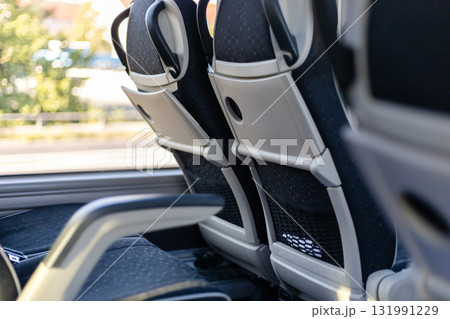 Inside the bus, rows of empty, comfortable seats are arranged with a sleek design. Sunlight filters through the windows, highlighting the peaceful scenery outside Inside the bus, rows of empty, comfortable seats are arranged with a sleek design. Sunlight filters through the windows, highlighting the peaceful scenery outside 131991229