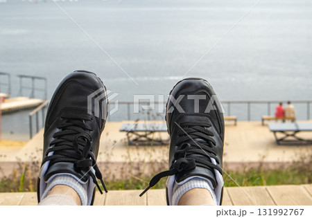 Black sneakers by the water POV on boardwalk horizontal composition 131992767