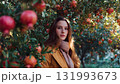 A woman farmer stands beneath a persimmon tree laden with bright red, juicy fruit, symbolizing bountiful harvest, nature's beauty, and organic produce. AI Generated 131993673