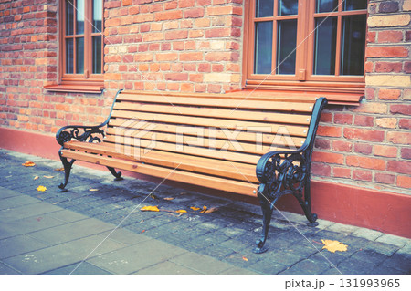 Wooden bench near an old brick building 131993965