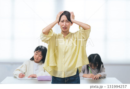 勉強する二人の女の子の前で悩む女性 131994257