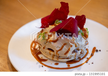 Fluffy pancake stack with cream, and salted caramel sauce, and topped red raspberry tuile 131995101