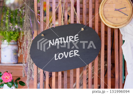 A black oval sign hangs, proclaiming Nature Lover. The setting is a rustic indoor space. Dried florals and plants adorn shelves, adding to the charming decor. A clock hangs nearby 131996094