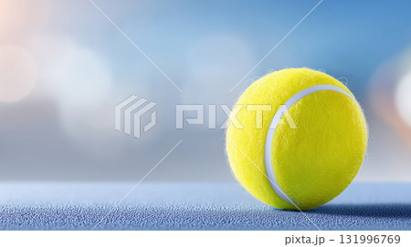 Vibrant tennis ball on a blue court with a bright, blurred background 131996769