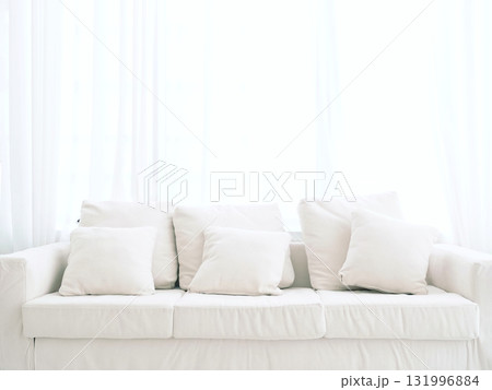 Plain white sofa in living room Decorated with white fabric pillows Behind it is a translucent curtain. Natural light shines through and makes it bright and clean. Plain white sofa in living room Decorated with white fabric pillows Behind it is a translucent curtain. Natural light shines through and makes it bright and clean. 131996884